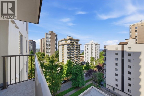 View from balcony showing city buildings, trees, and blue sky with clouds. - 802 1251 Cardero Street, Vancouver
