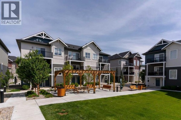 Courtyard view of apartment buildings with landscaping and seating. - 803, 24 Rivercrest Drive, Cochrane
