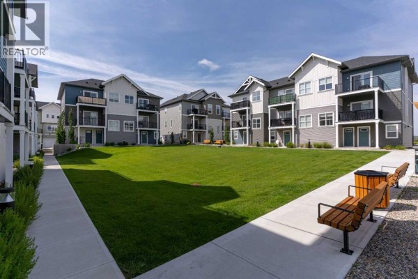 Wide view of the apartment complex courtyard with grassy lawn. - 803, 24 Rivercrest Drive, Cochrane