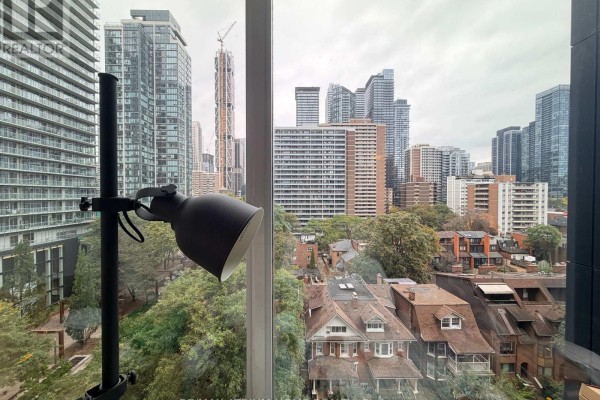View from apartment window showing Toronto skyline, trees, and older houses below. - 803 - 17 Dundonald Street, Toronto