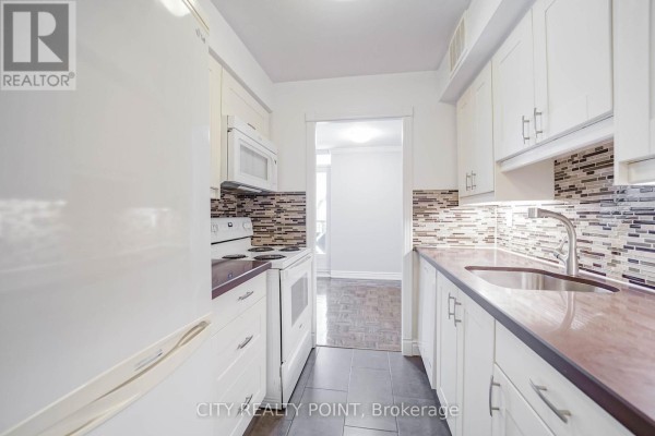 Kitchen with white cabinetry, a stainless steel sink, and dark countertops. - 803 - 55 Isabella Street, Toronto