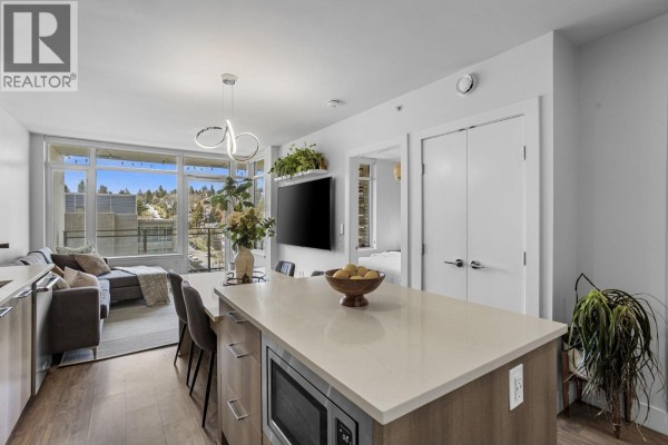 Open-concept space with kitchen island, living area, and access to outdoor balcony - 803 258 Nelson's Court, New Westminster