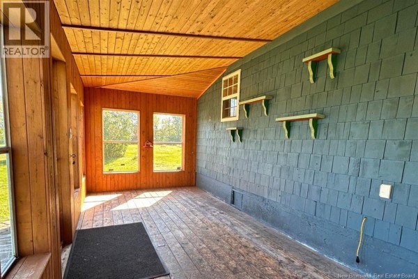 Bedroom with patterned wallpaper, dark wood wainscoting, and a small window. - 8034 Route 134, Galloway