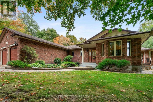 Close-up of the brick house facade with a walkway and manicured greenery leading to the entrance. - 8036 Marionville Road, North Dundas