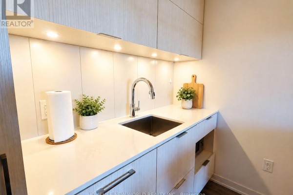 Close-up of the kitchen sink with white countertops, modern faucet, and stainless steel basin. - 804 - 20 Richardson Street, Toronto