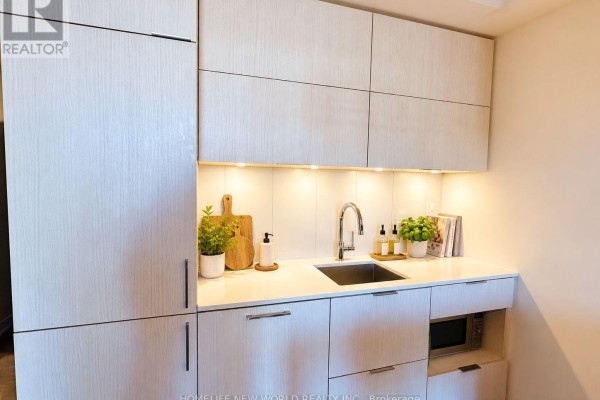 Kitchen with a stainless steel sink, white countertops, and integrated microwave and oven. - 804 - 20 Richardson Street, Toronto