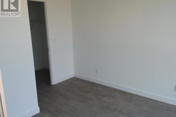 Interior view of a room with white walls, gray wood-look flooring, and electrical outlets. - 804 - 2055 Danforth Avenue, Toronto