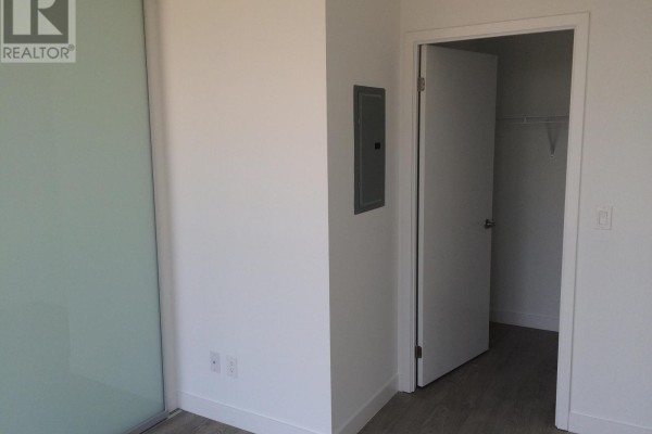Apartment corner with white walls, gray wood-look flooring, and a sliding glass door. - 804 - 2055 Danforth Avenue, Toronto