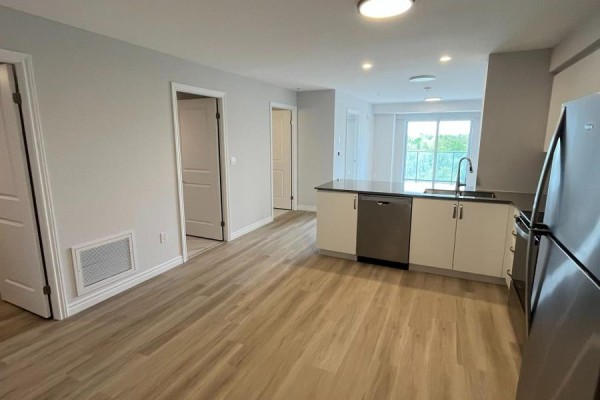 Open concept living area with kitchen island, stainless steel dishwasher, and access to balcony. - 804 - 425 Watson Parkway N, Guelph