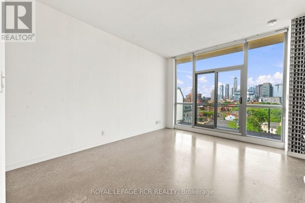 Empty room with large windows offering a panoramic view of the Toronto skyline. - 804 - 510 King Street E, Toronto
