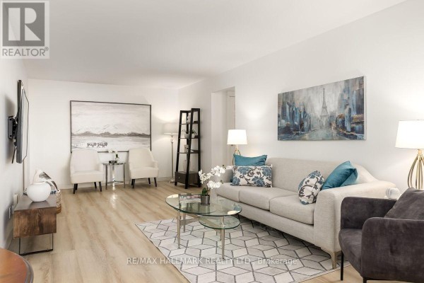 Living room with beige carpet, dark blue walls, leather armchairs, and decorative artwork. - 804 - 980 Broadview Avenue, Toronto