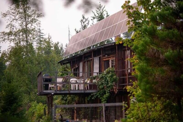 Wooden cabin exterior with a deck, outdoor seating, and solar panels on the roof. - 804 Applegrove Road, Fauquier