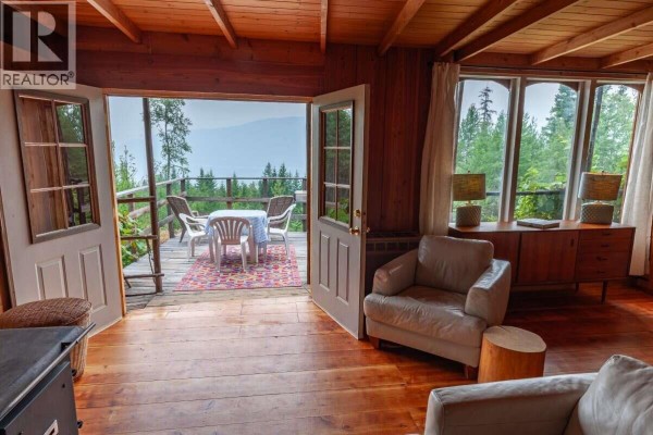 Living room interior with wood floors, large windows, fireplace, and double doors opening to a deck. - 804 Applegrove Road, Fauquier