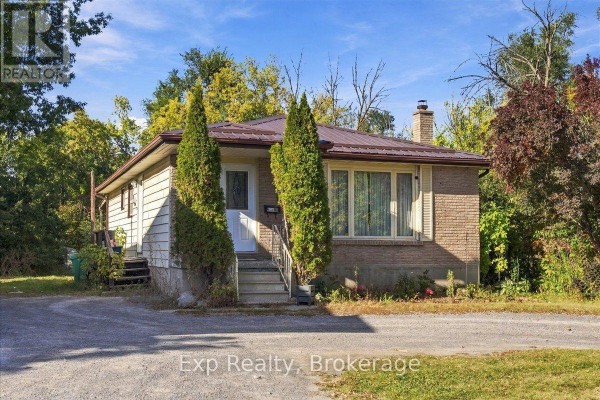 Side exterior view of the bungalow showing brick and siding with trees and driveway. - 804 Sherbrooke Street, Peterborough