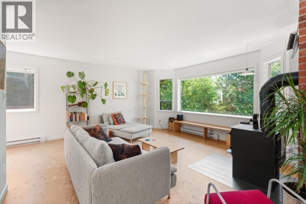 Living room with a grey sectional sofa, chaise lounge, large window, and wood floor. - 8044 Dogwood Drive, Halfmoon Bay