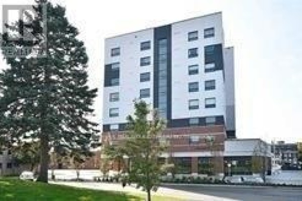 Side view of an apartment building with large trees and a street. - 805 - 1 Wellington Street, Brantford