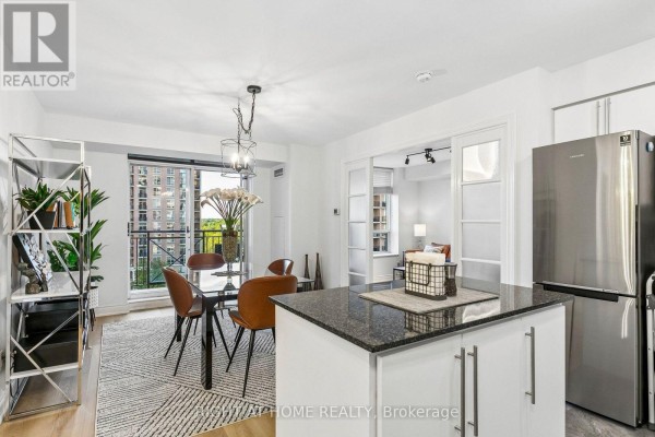 Open concept living and dining area with a kitchen island, dining table, and balcony access. - 805 - 1103 Leslie Street, Toronto