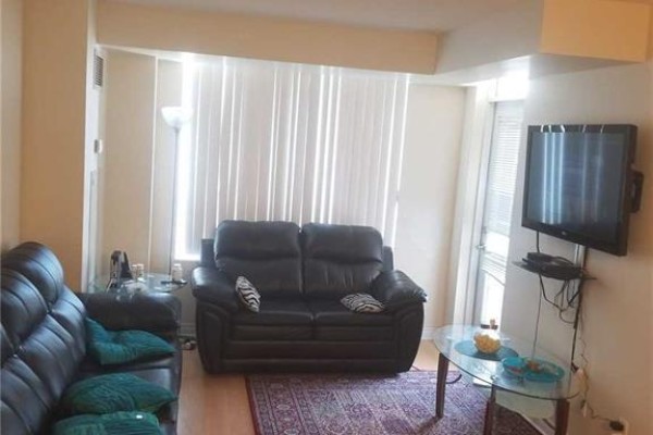 Living room with two black leather sofas, a glass coffee table, and vertical blinds. - 805 - 310 Burnhamthorpe Road W, Mississauga