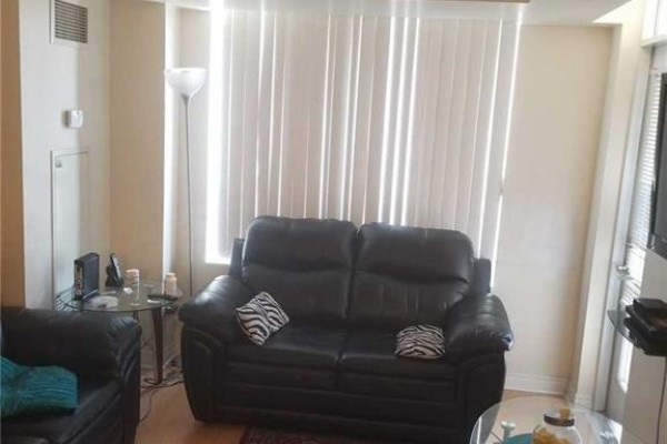 Living room with black leather sofas, glass coffee table, and vertical blinds on window. - 805 - 310 Burnhamthorpe Road W, Mississauga