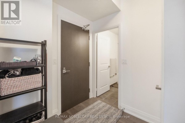 Hallway entrance with a dark brown door and view into the bathroom. - 805 - 3600 Highway 7 Road, Vaughan