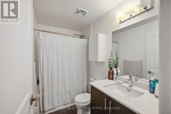 Bathroom with a vanity, toilet, shower curtain, and mirror. - 805 - 3600 Highway 7 Road, Vaughan