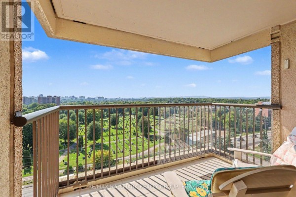 Balcony view overlooking a green park area with trees and distant cityscape under a blue sky. - 805 - 545 St Laurent Boulevard, Ottawa