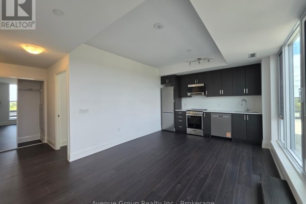 Open concept living area with dark wood floors and a dark kitchen. - 805 - 700 Sheppard Avenue W, Toronto