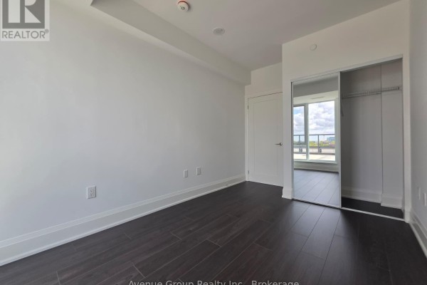 Bedroom with white walls, dark floors, and a mirrored closet. - 805 - 700 Sheppard Avenue W, Toronto