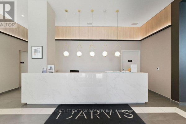 Concierge desk with a marble counter, modern pendant lights, and a welcome mat. - 806 - 1 Jarvis Street, Hamilton