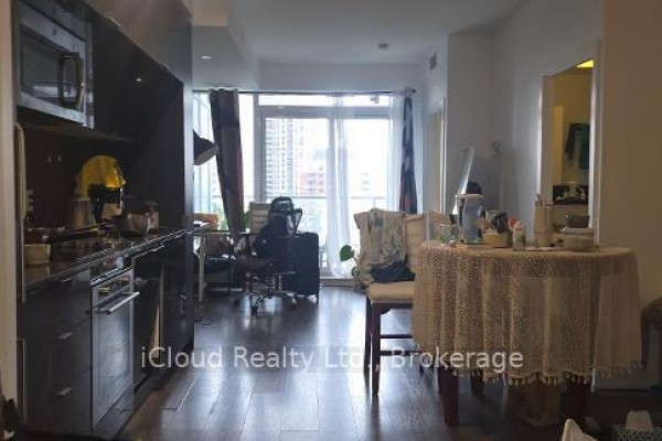 Open concept living area with a dining table, desk, and balcony access. - 806 - 28 Avondale Avenue, Toronto