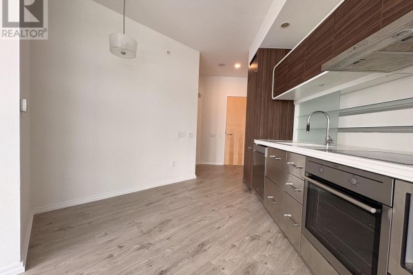 Open concept living space with a kitchen, light wood floors, and plain walls. - 806 - 45 Charles Street E, Toronto