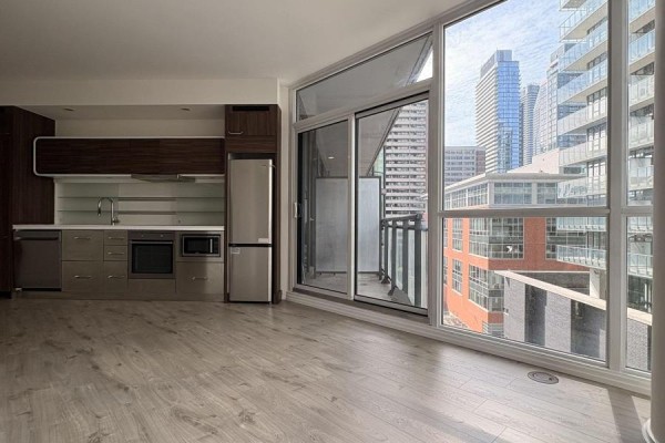 Apartment living area with a kitchen, large windows, balcony access, and city views. - 806 - 45 Charles Street E, Toronto