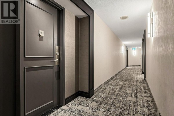 Hallway with beige textured wallpaper, patterned carpet, and doorways. - 806 - 7460 Bathurst Street, Vaughan