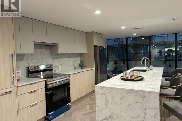 Modern kitchen with light wood cabinets, marble countertops, stainless steel appliances, and an island. - 806 10333 133 Street, Surrey