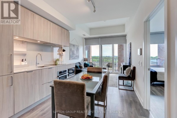 Kitchen and dining area overlooking a balcony with city and tree views. - 807 - 28 Ann Street, Mississauga