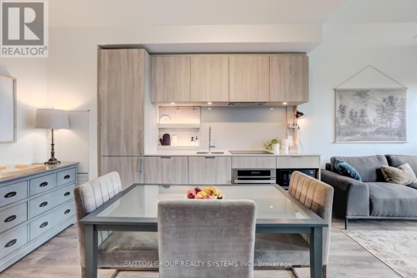 Dining area with a glass-top table and chairs, next to a grey dresser and kitchen cabinetry. - 807 - 28 Ann Street, Mississauga