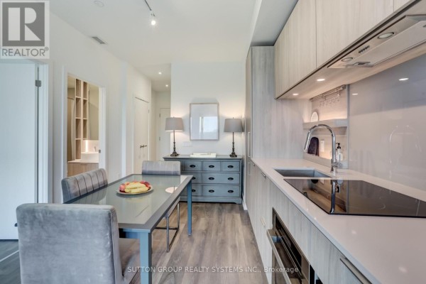 Kitchen with light wood cabinets, stainless steel appliances, and a grey dining set. - 807 - 28 Ann Street, Mississauga
