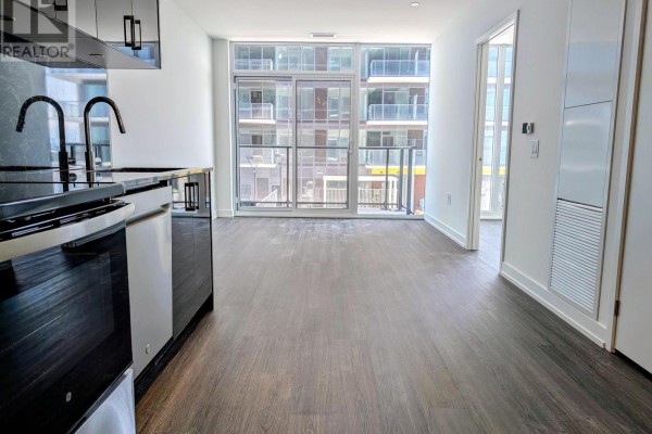 Apartment living area with dark wood floors and a view of balconies through glass doors. - 807 - 4010 Eglinton Avenue W, Toronto