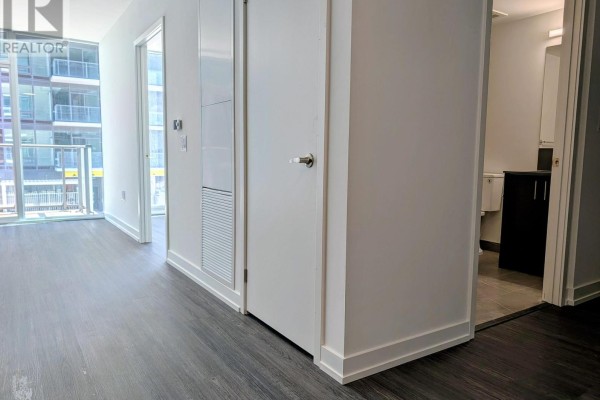 Hallway with white doors, dark wood floors, and a view into a bathroom. - 807 - 4010 Eglinton Avenue W, Toronto