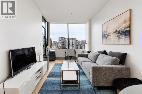 Living area with grey sofa, modern television stand, and large windows. - 807 1010 Howe Street, Vancouver