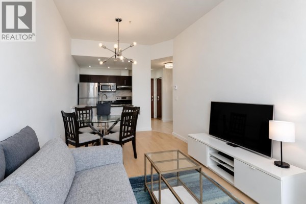 Living area, dining table, and kitchen with stainless steel appliances. - 807 1010 Howe Street, Vancouver