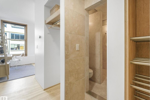 View into a bathroom with beige tiled walls and a toilet, next to a closet. - #807 10134 100 St Nw, Edmonton