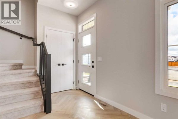Front entryway with white doors, modern glass door, and herringbone wood floor. - 807 Sora Boulevard Se, Calgary