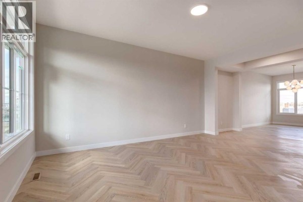 Spacious living room with large windows, light neutral walls, and herringbone wood flooring. - 807 Sora Boulevard Se, Calgary