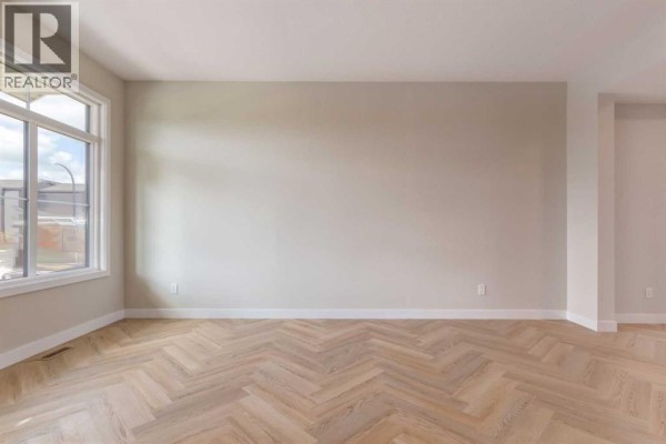 Empty living room featuring large windows, neutral walls, and light-coloured wood flooring. - 807 Sora Boulevard Se, Calgary