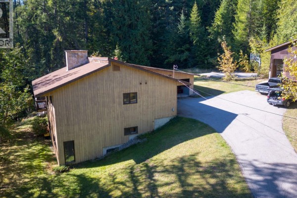 Aerial view of the property showing the house, garage, driveway and surrounding forest. - 807 Spokane Street, Rossland