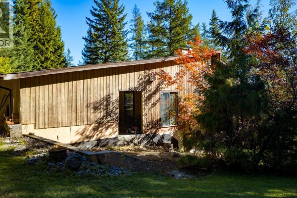 Rear view of the house exterior with wood siding and a sloping roofline. - 807 Spokane Street, Rossland