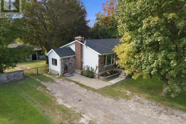 Aerial view of the stone and white sided bungalow with driveway and fence. - 8074 Tinkerville Road, Port Hope