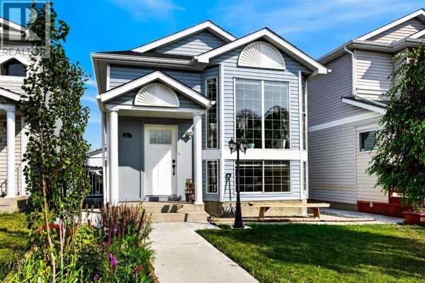 Front exterior of a light blue house with white trim and columns. - 8079 Laguna Way Ne, Calgary