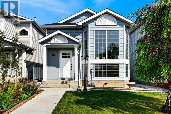 View of the front of a light blue house with a large bay window and front entrance. - 8079 Laguna Way Ne, Calgary